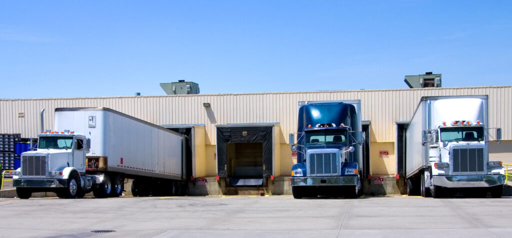 Dry van trailers backed into loading dock doors at a warehouse, being loaded with freight