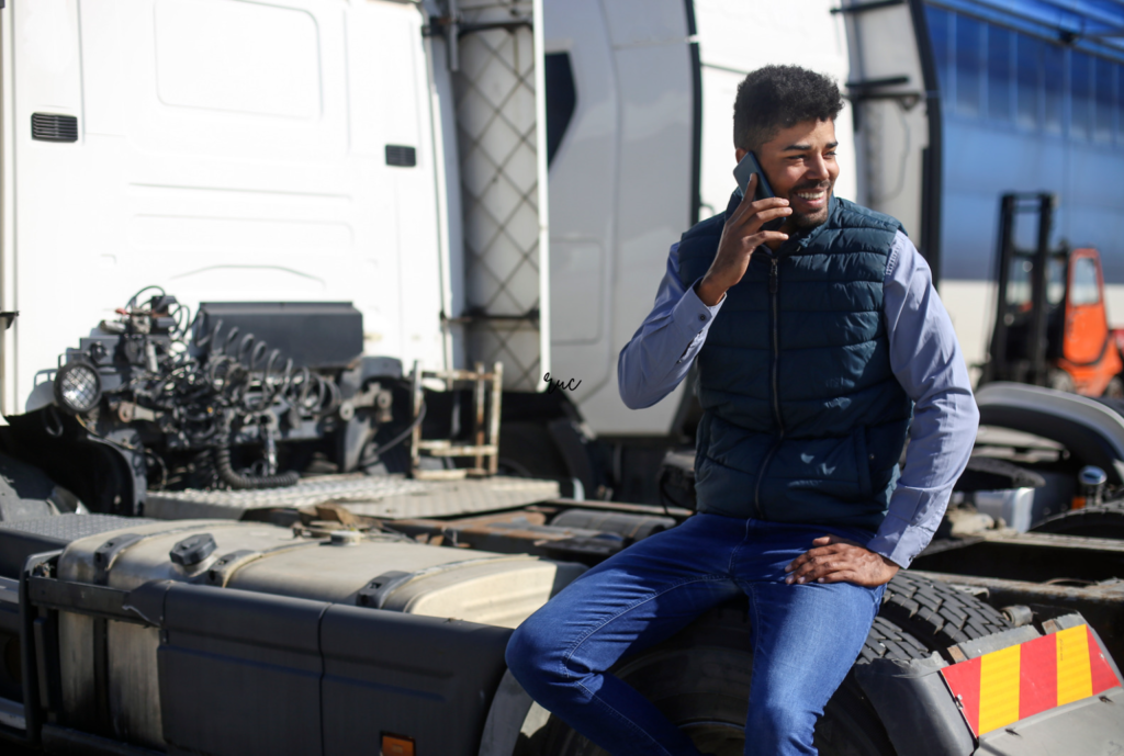 truck driver holding phone sitting in a truck