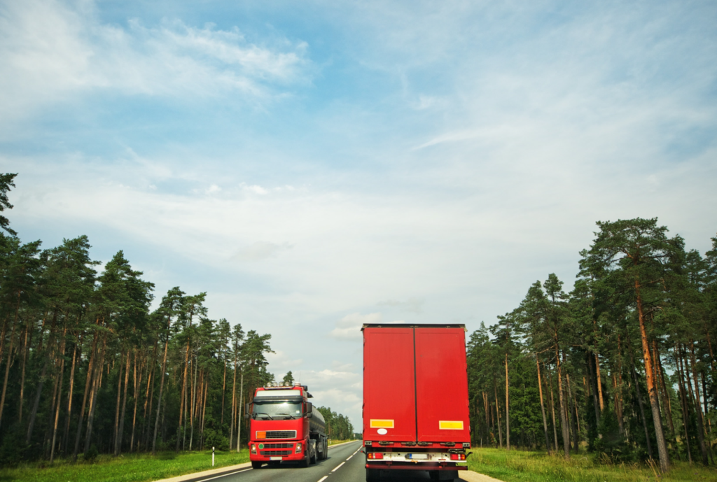 two red trucks driving in the road