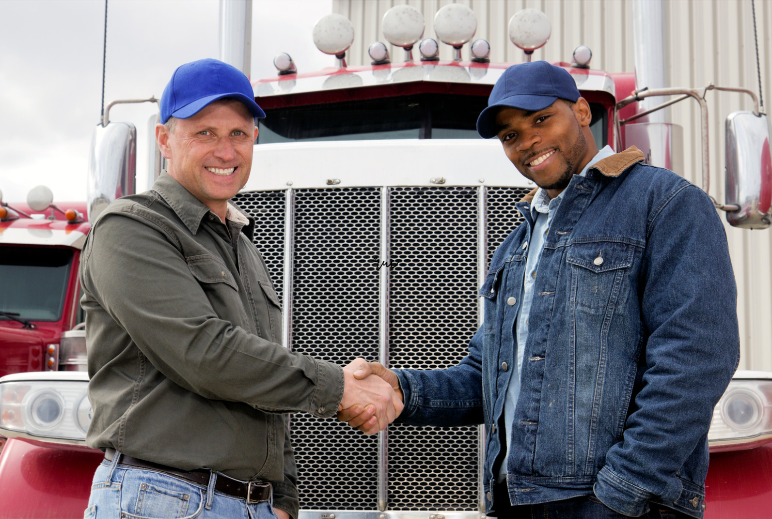 two truck drivers shaking hands in front of truck