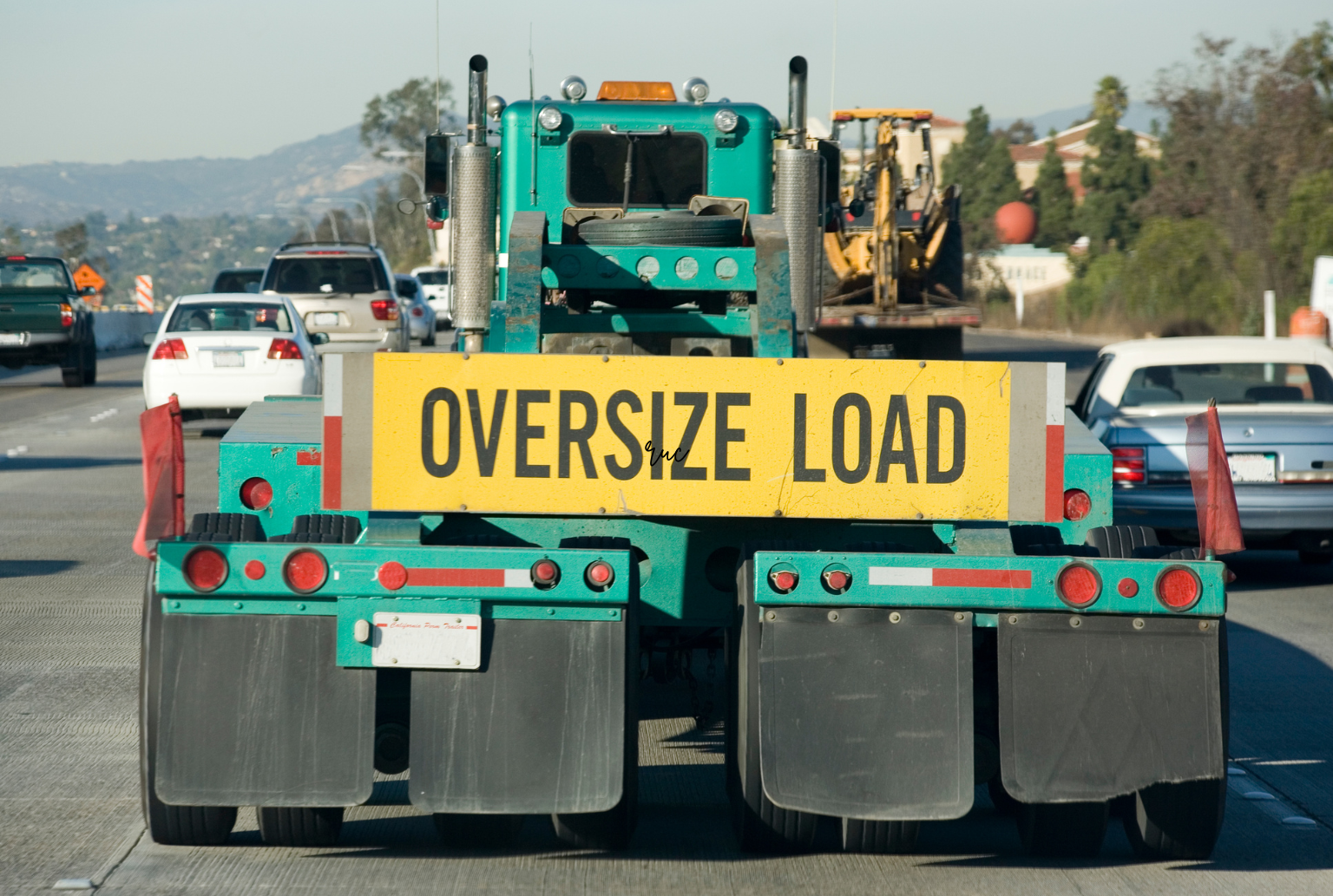 green oversized load trucking on the road