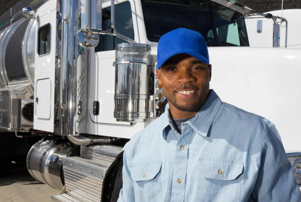 truck driver wearing blue cap in front of semitruck