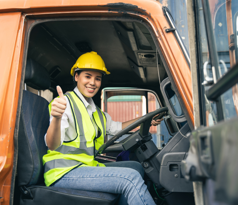 female truck driver wearing safety hat in truck