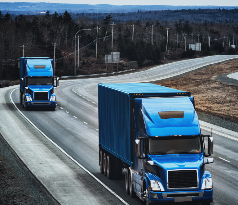 two blue trucks driving down the road