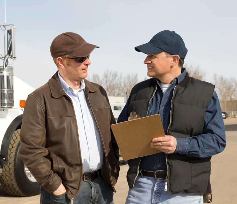 two truck drivers talking while holding files